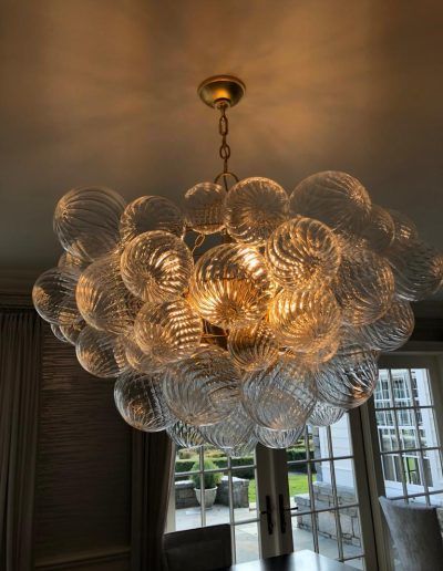 Large, round glass chandelier with textured, swirling globes; hanging from a gold chain.