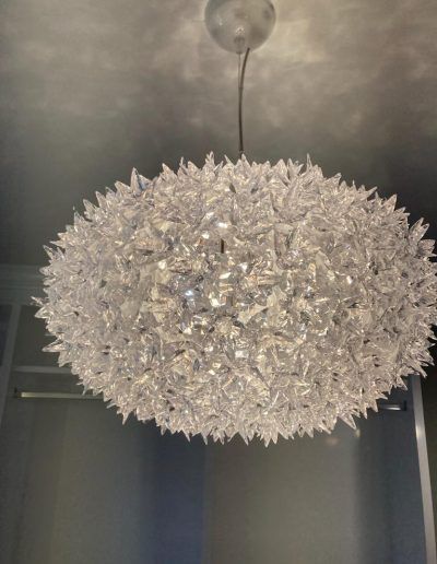 A modern, spiky, globe-shaped pendant light fixture hanging from a ceiling.