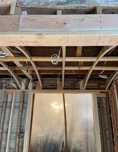 Wooden framing, including curved beams, over a doorway. Wires are visible.