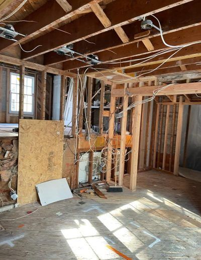 Interior room under construction, exposed wooden framing, electrical wiring, unfinished walls and ceiling.