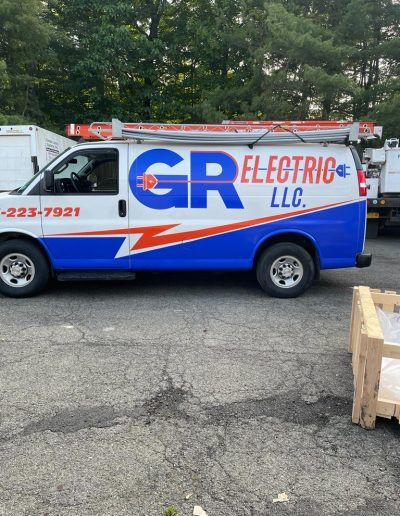 White and blue GR Electric van with red lightning bolt, parked outdoors.