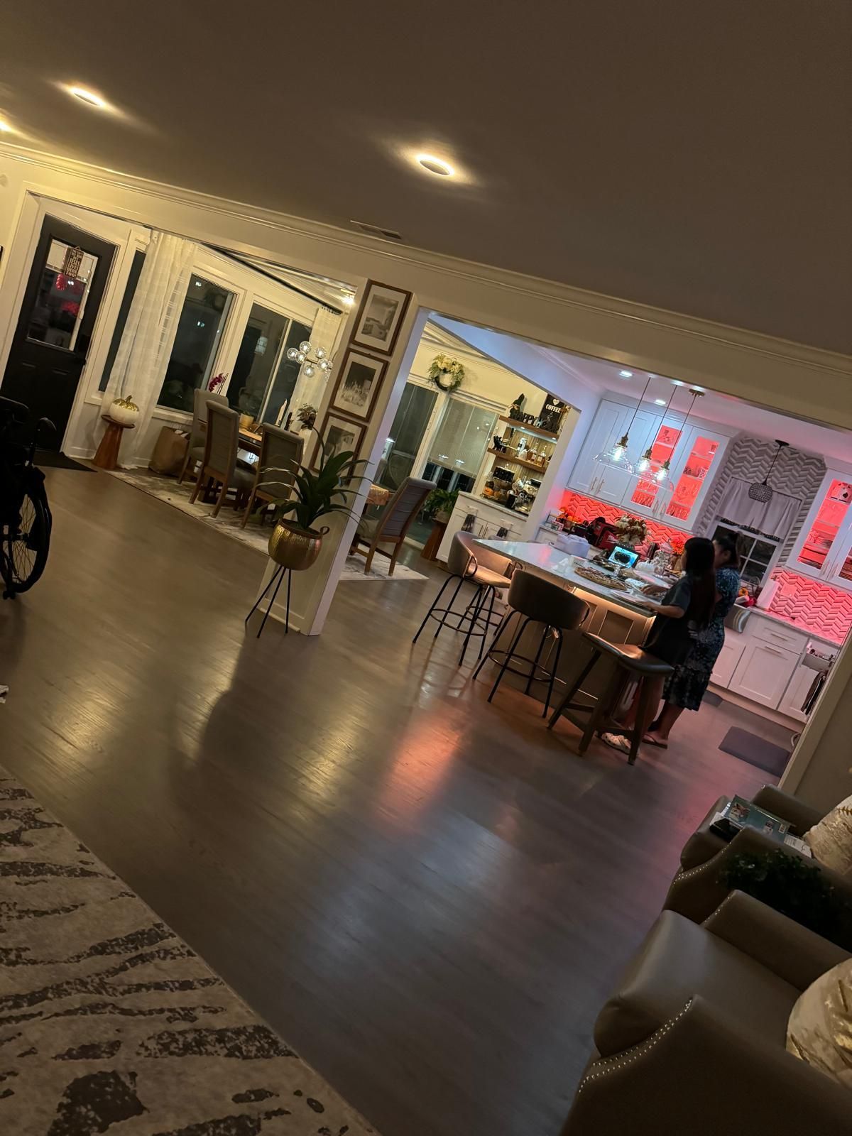 Spacious, well-lit kitchen and dining area with hardwood floors. A person stands at the kitchen island.