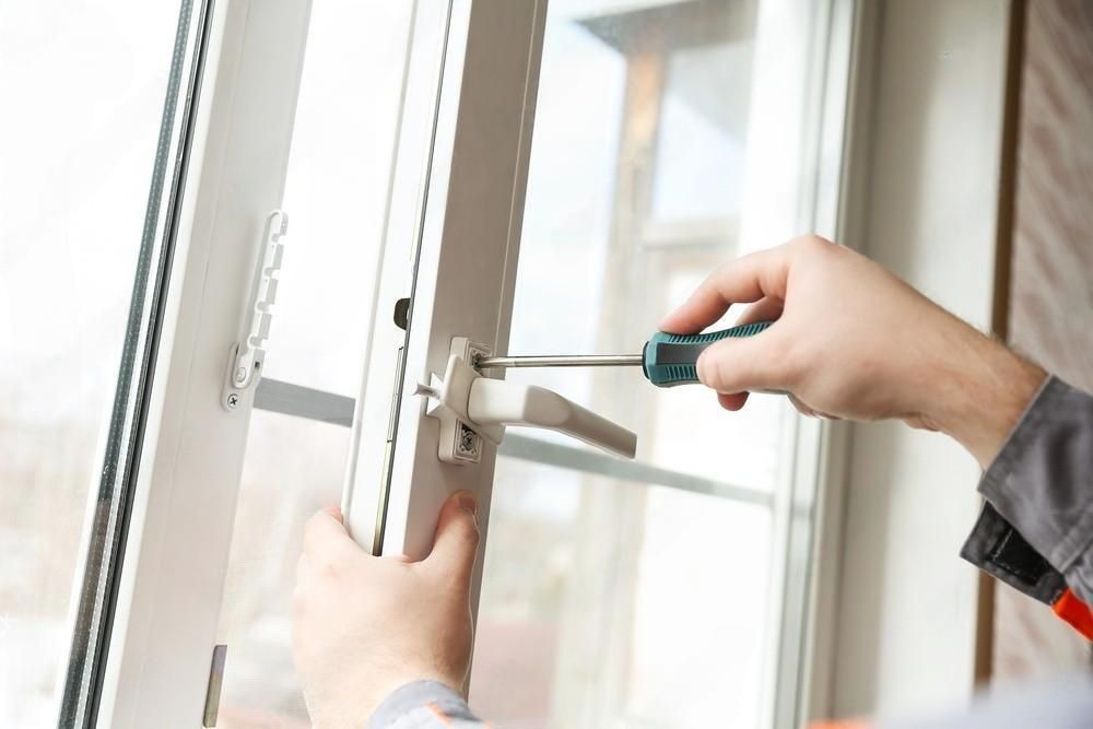 A person is fixing a window with a screwdriver.