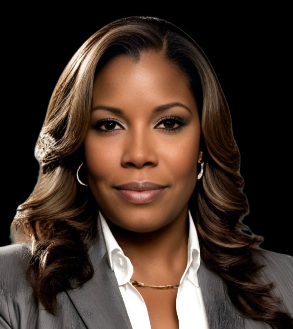 Black woman with brown hair wearing a gray suit and a white shirt, smiling, on a black background.