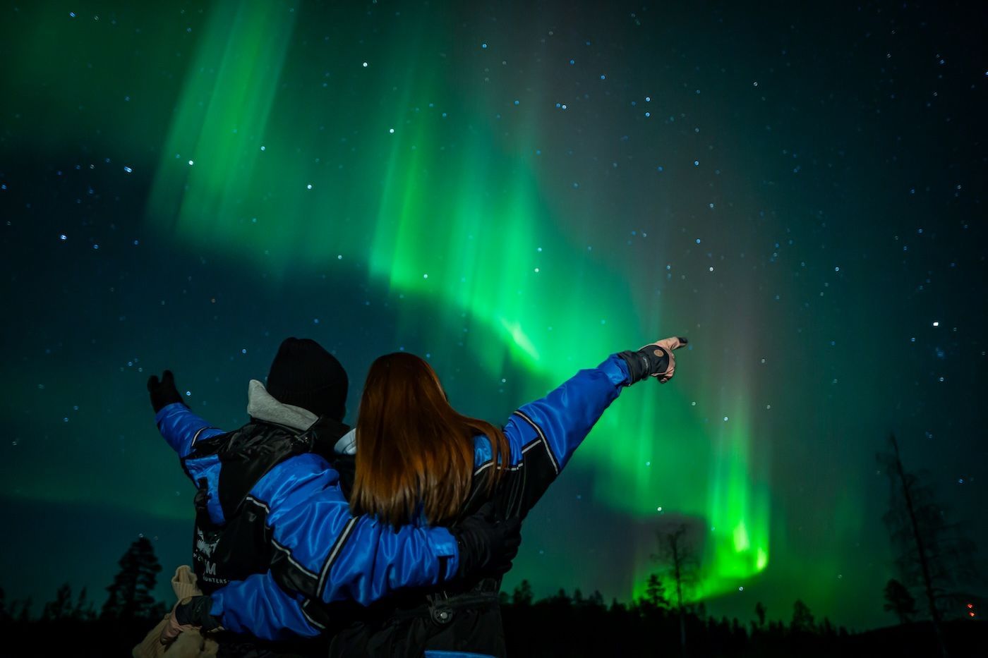 Guests pointing at Aurora sky during Arctic GM guided Northern Lights chase in Tromsø
