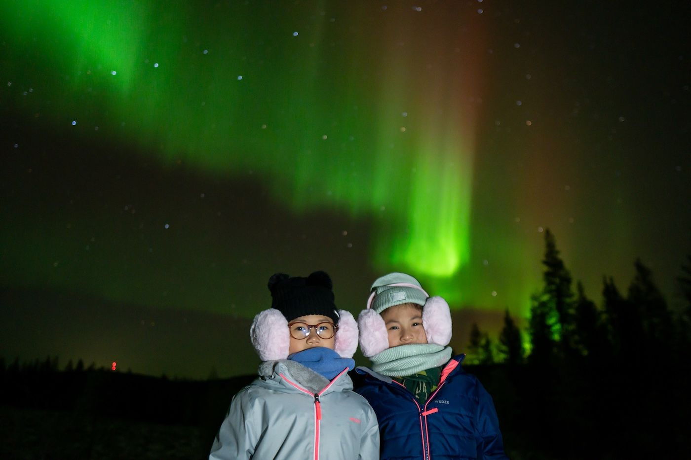 Children watching the Northern Lights during a family-friendly Arctic GM tour in Rovaniemi