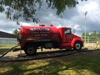 A red septic truck is parked on the side of the road.