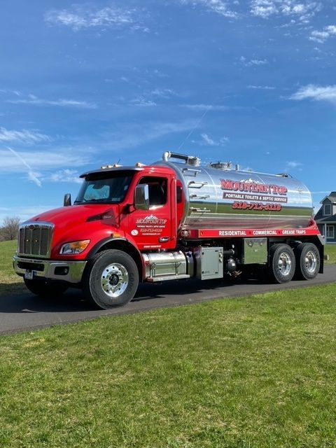 A red and silver truck is parked on the side of the road.