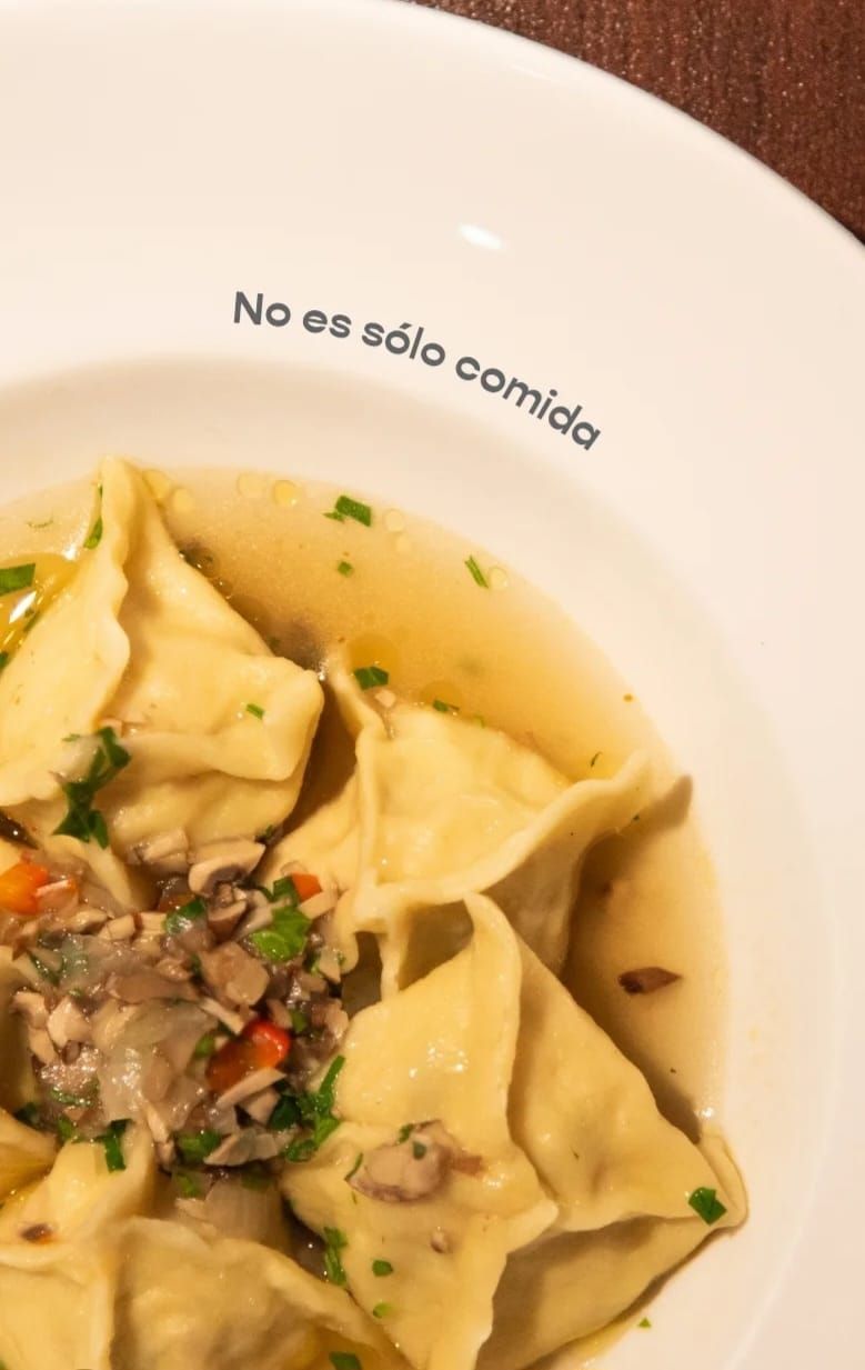 Primer plano de un tazón blanco lleno de sopa y dumplings. Texto 