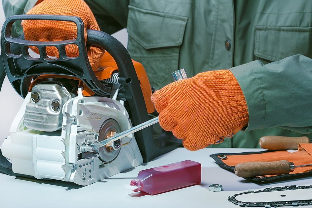 A Man Wearing Orange Gloves Is Holding a Chainsaw — Stihl Shop Grafton in Grafton, NSW