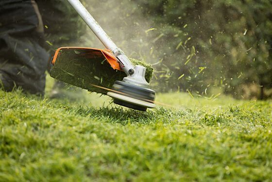 A Person Is Using a Lawn Mower to Cut the Grass — Stihl Shop Grafton in Grafton, NSW