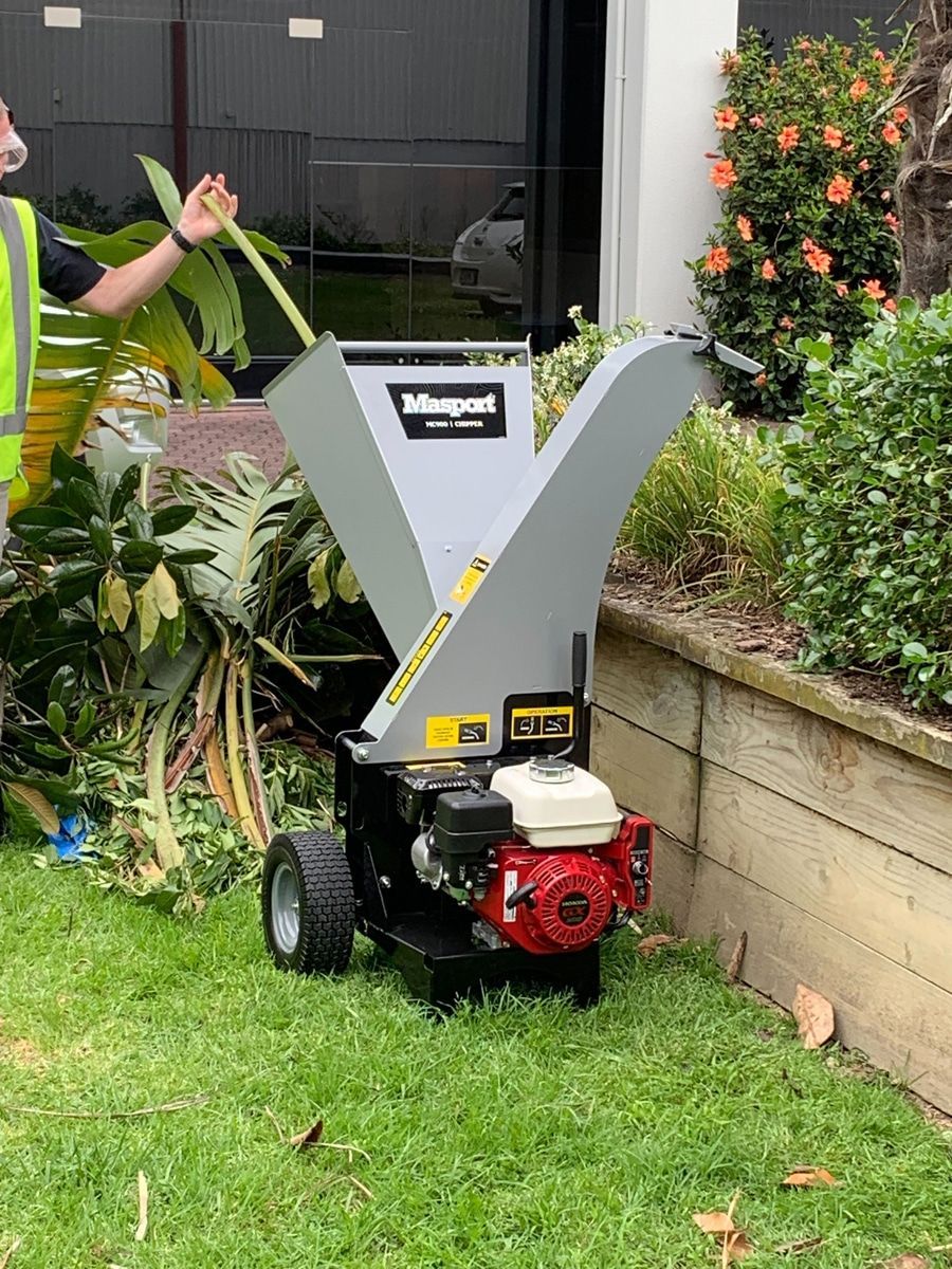 A Man Is Standing Next to A Tree Chipper in A Yard — Stihl Shop Grafton in Grafton, NSW