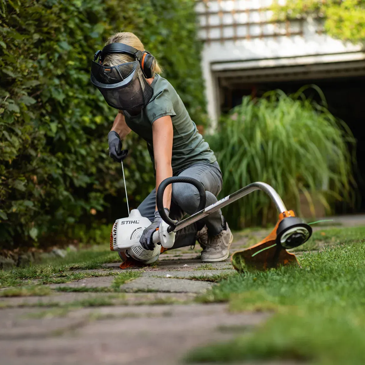 A Woman Is Kneeling Down While Using a Lawn Mower — Stihl Shop Grafton in Grafton, NSW