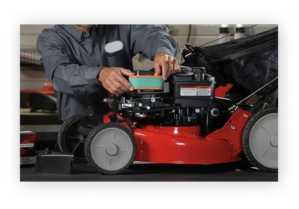 A Man Is Working on A Lawn Mower in A Garage — Stihl Shop Grafton in Grafton, NSW