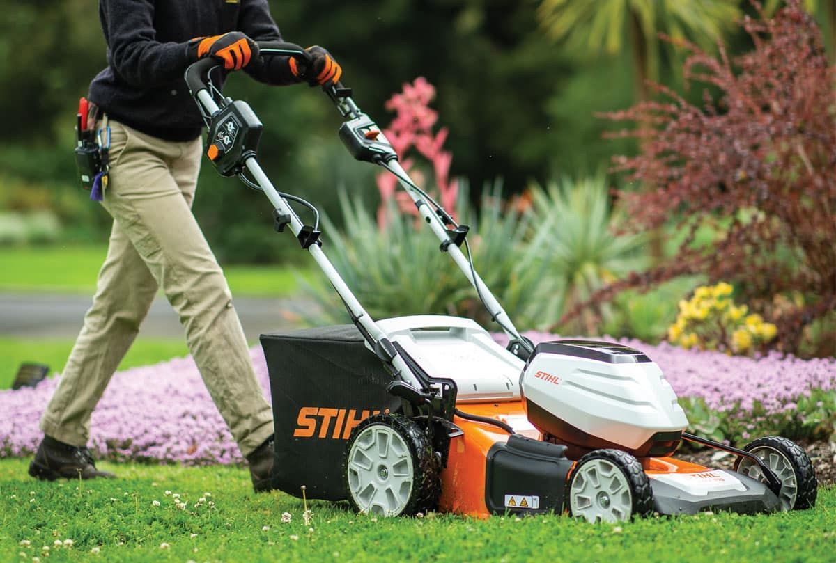 A Person Is Using a Stihl Lawn Mower on A Lush Green Lawn — Stihl Shop Grafton in Woolgoolga, NSW