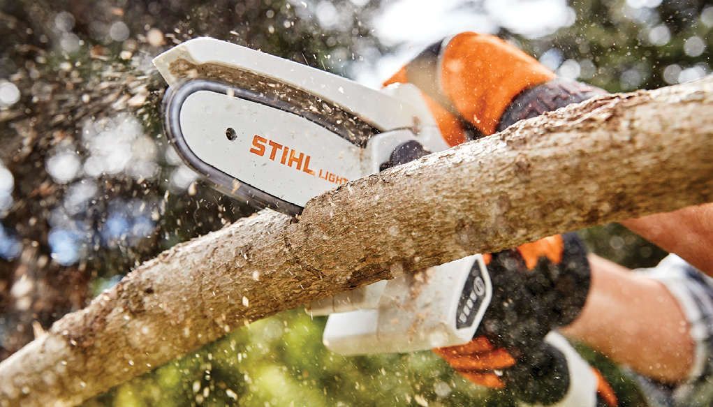 A Person Is Cutting a Tree Branch with A Chainsaw — Stihl Shop Grafton in Grafton, NSW