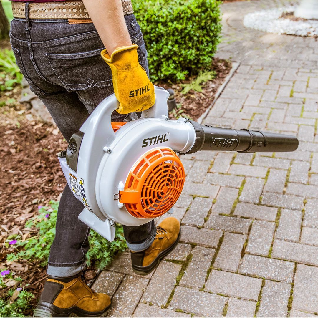 A Person Is Carrying a Stihl Blower on A Sidewalk — Stihl Shop Grafton in Grafton, NSW