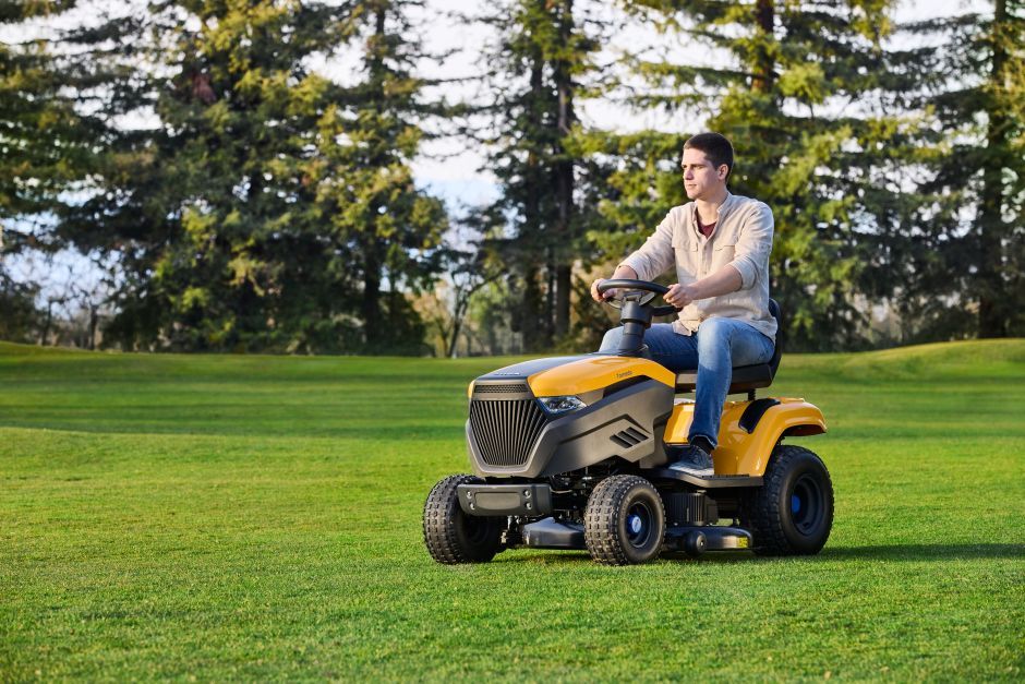 A Man Is Riding a Lawn Mower on A Lush Green Field — Stihl Shop Grafton in Clarence Valley, NSW