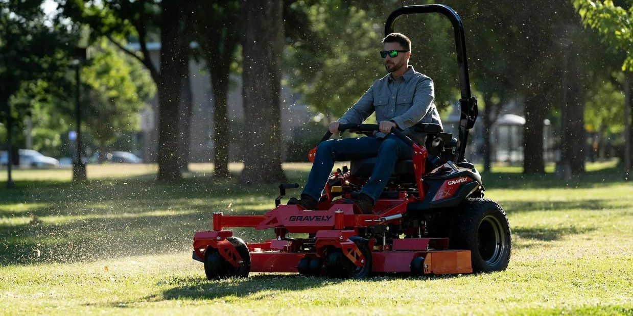 A Man Is Riding a Lawn Mower in A Park — Stihl Shop Grafton in Yamba, NSW