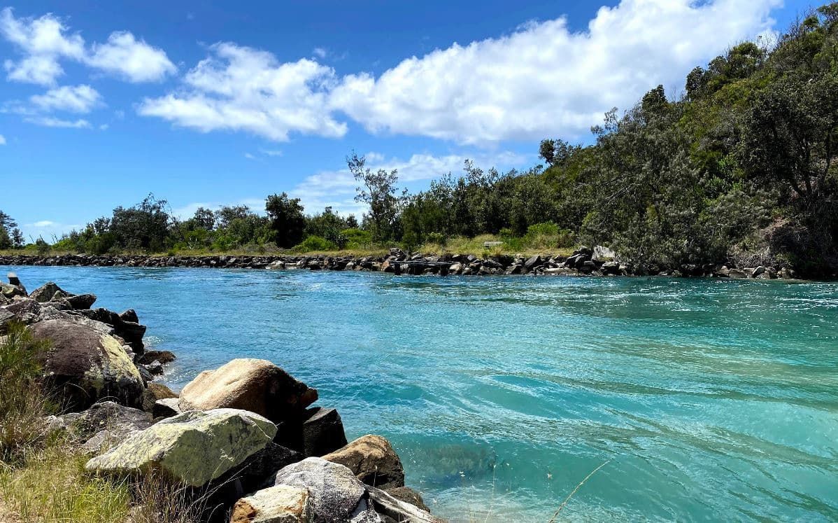 A Large Body of Water Surrounded by Rocks and Trees on A Sunny Day — Stihl Shop Grafton in Wooli, NSW