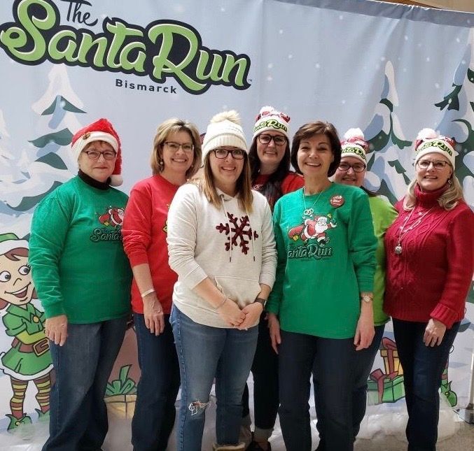 Group of women at The Santa Run Bismarck, wearing holiday sweaters and hats.