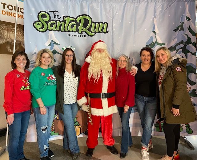 People pose with Santa Claus in front of a holiday backdrop at 