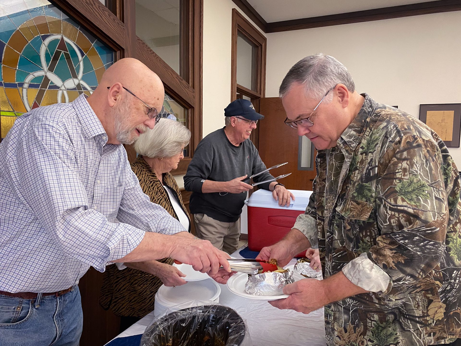 A group of men are standing around a table eating food.