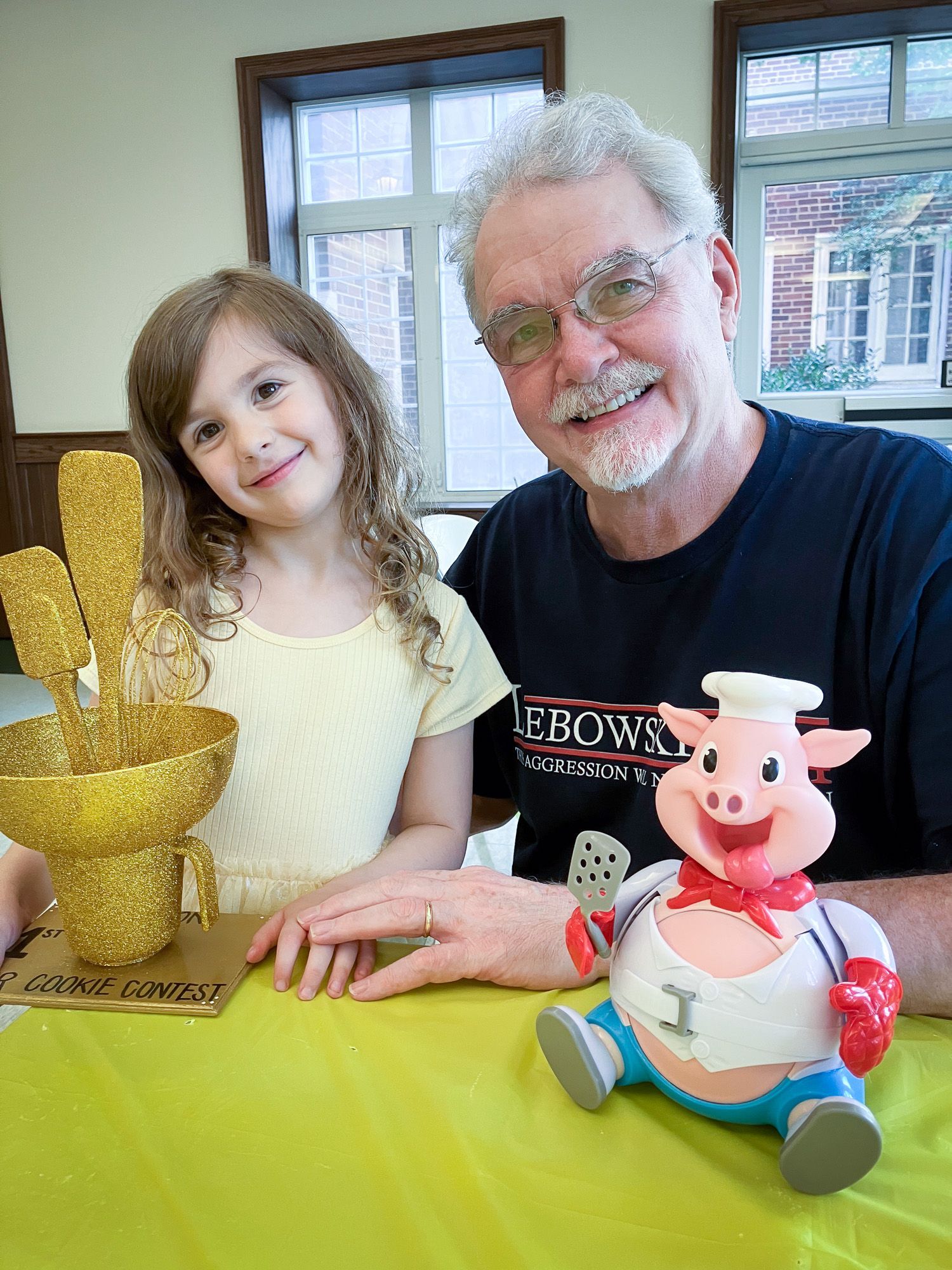 A man and a little girl are sitting at a table with a toy pig