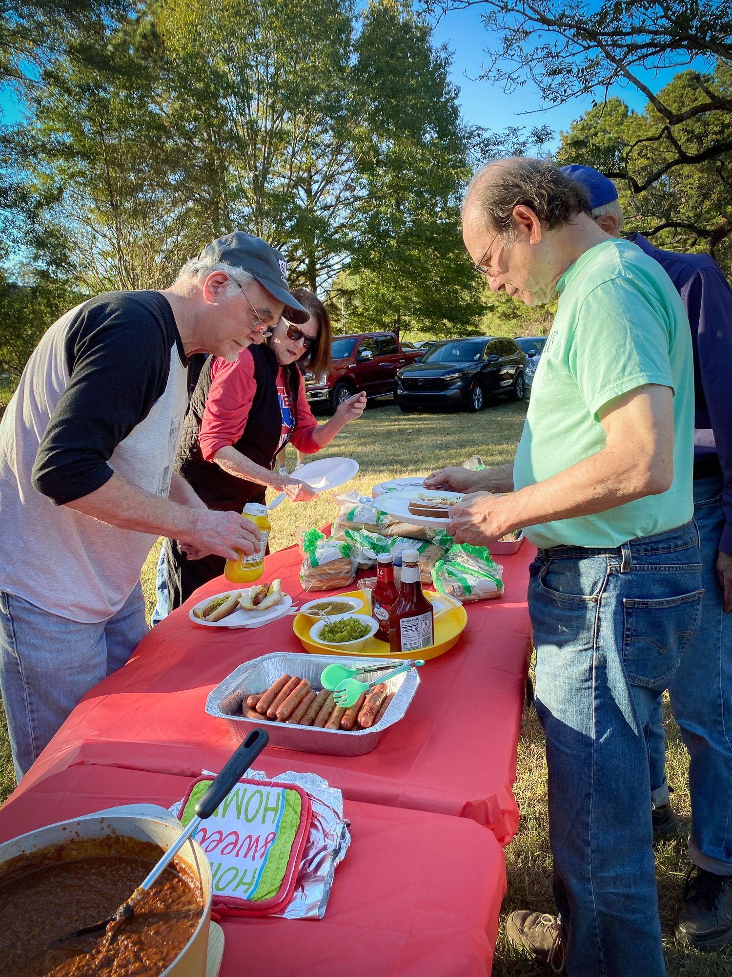 A group of people are standing around a table eating food.