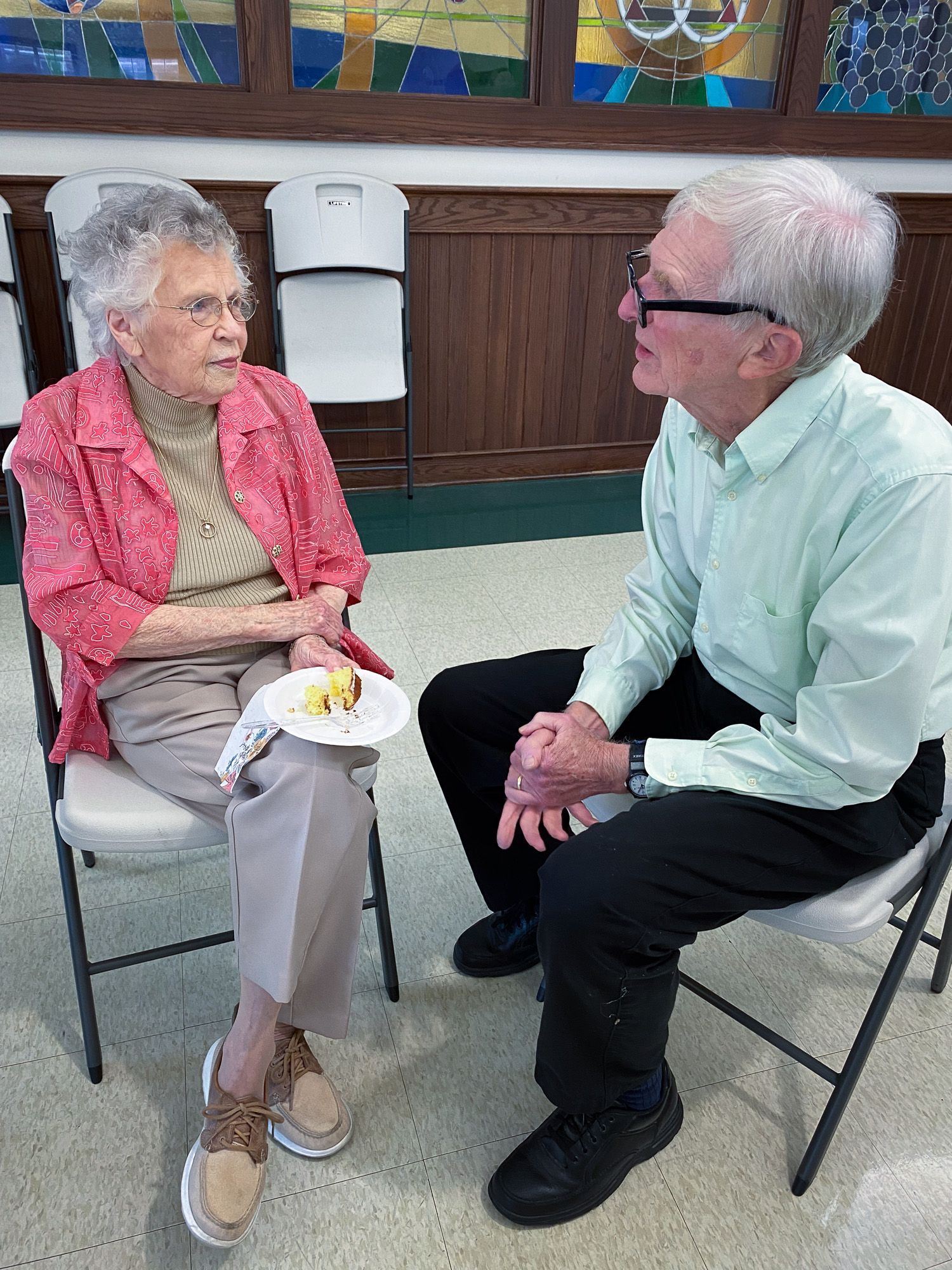 A man and a woman are sitting in chairs talking to each other.
