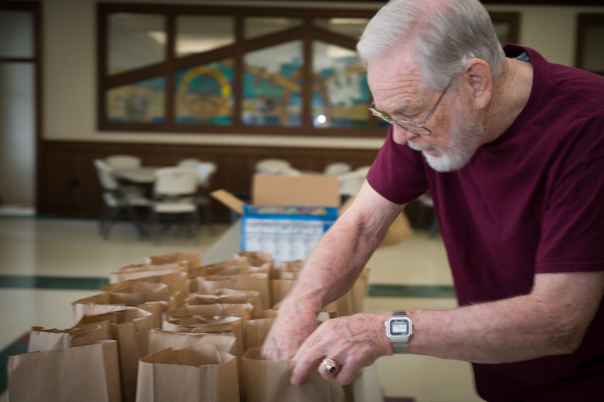 A man is standing in front of a table filled with brown bags.