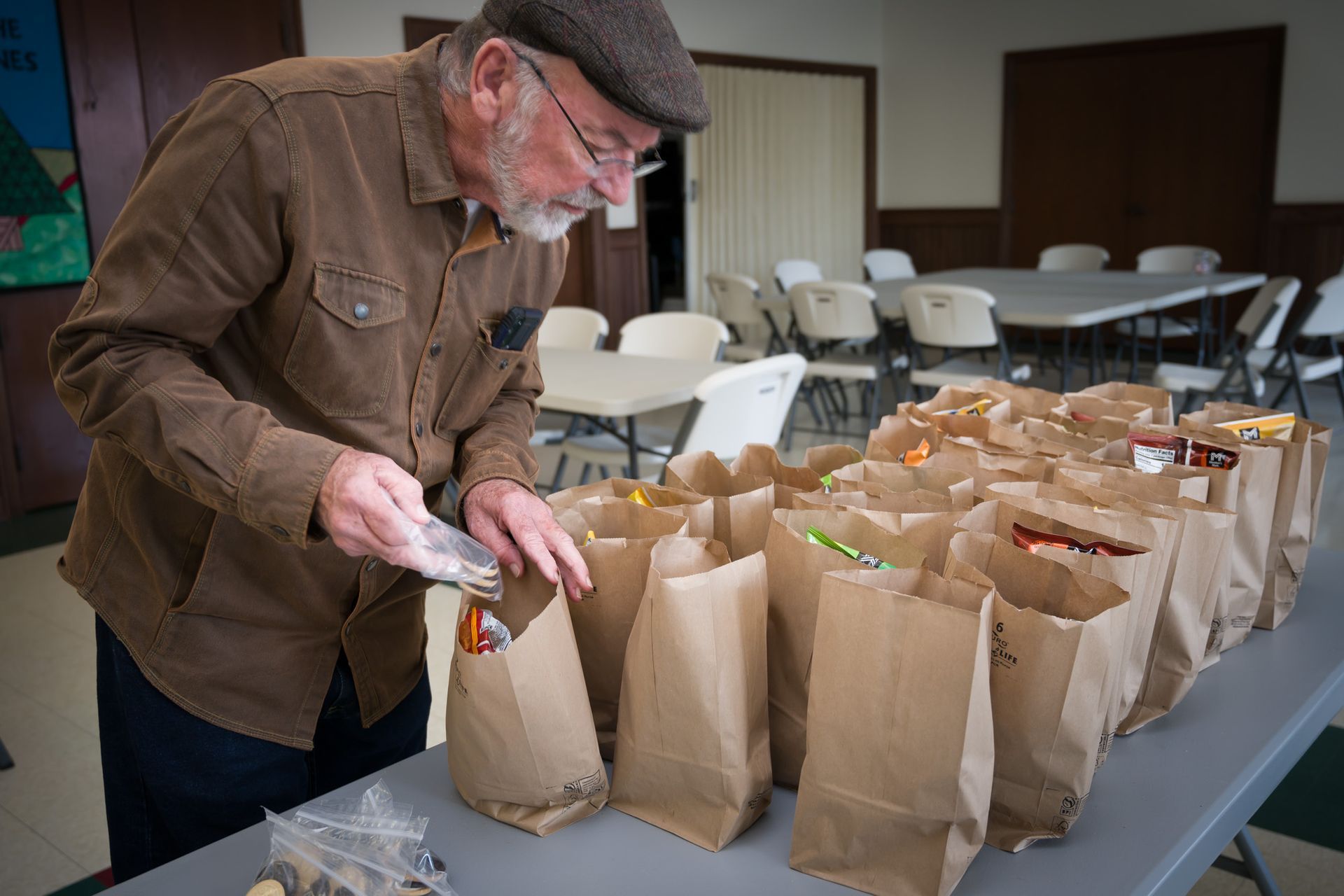 A man is putting something in a brown paper bag