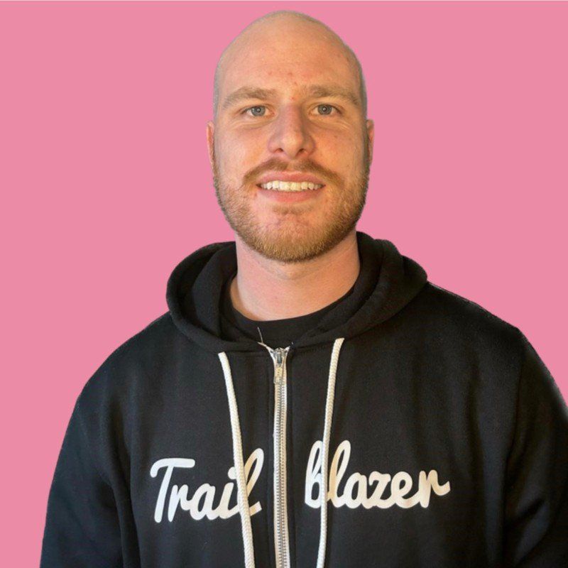 A bald man wearing a black trail blazer hoodie