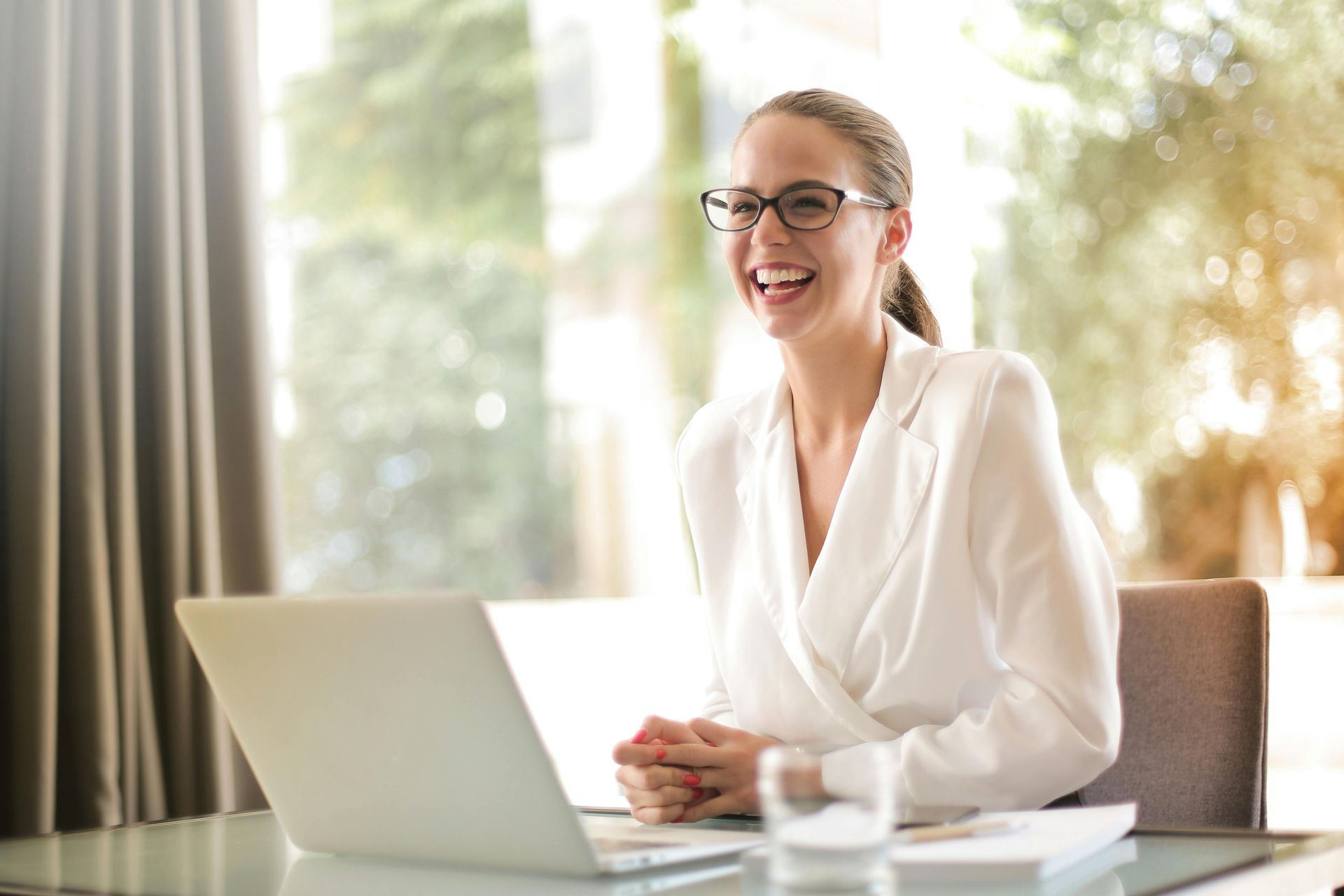 A woman is sitting at a desk in front of a laptop computer.
