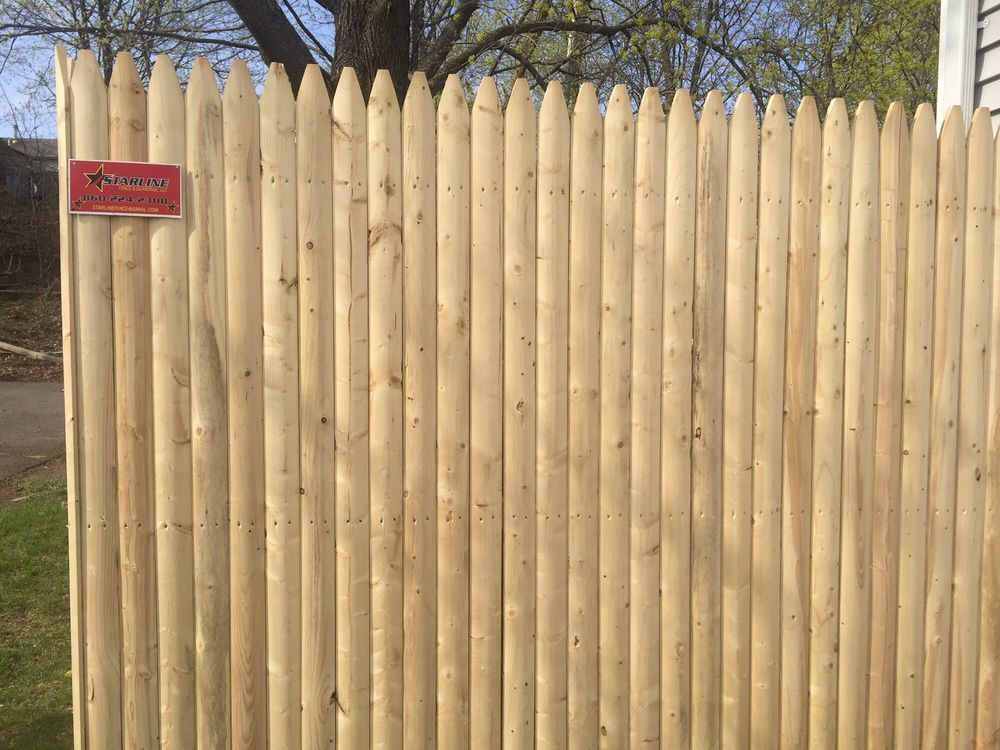 Wooden picket fence with pointed tops and a small sign.