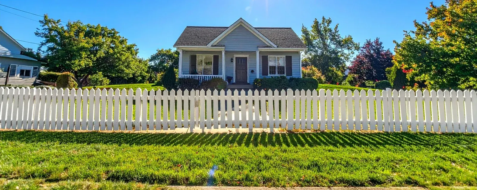 White picket fence along a suburban street, houses in background.