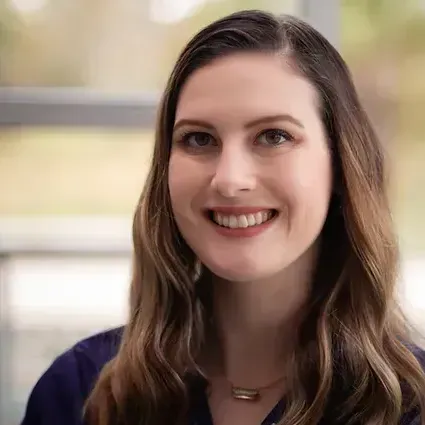 A woman with long hair is smiling for the camera.