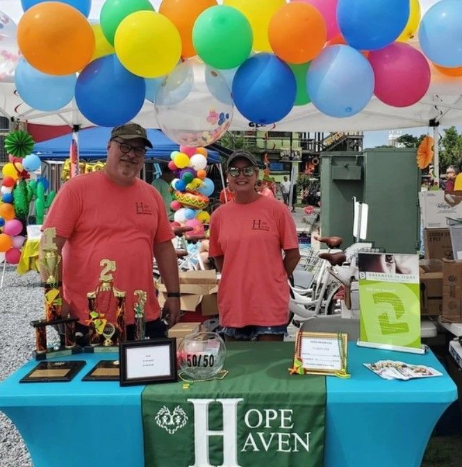 Two people standing in front of a table that says ope haven