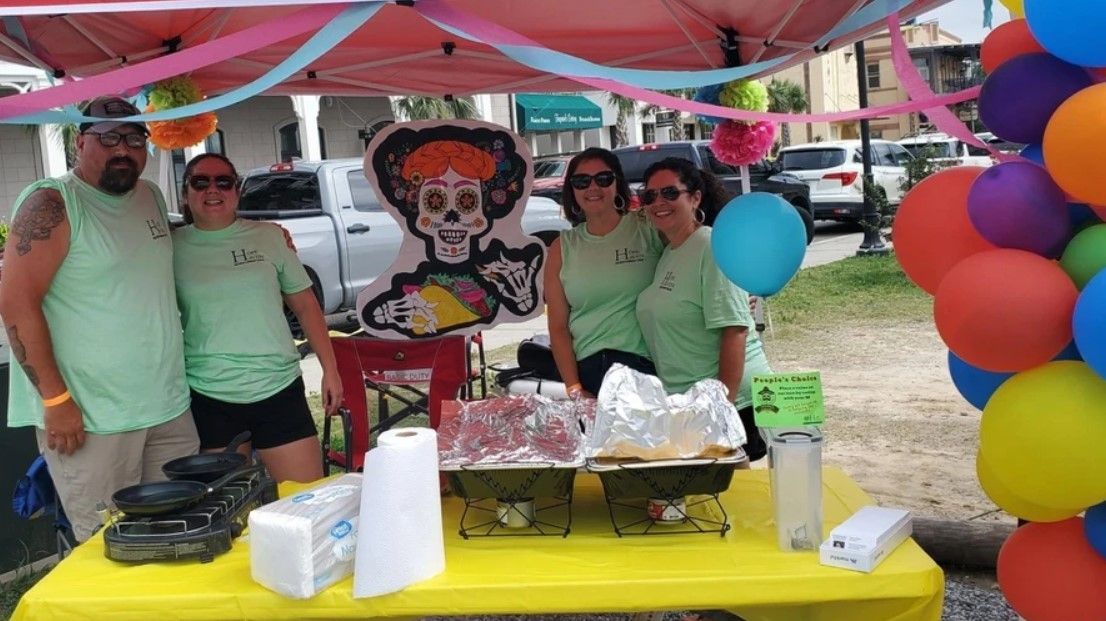 A group of people standing around a table with balloons.