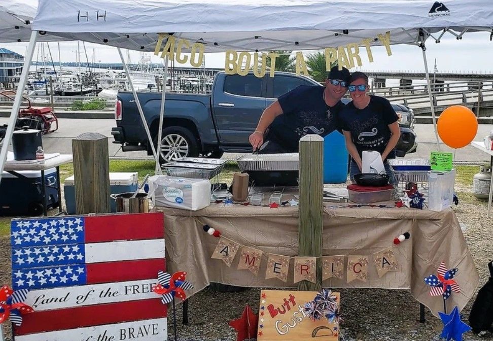 Two men are standing behind a table with an american flag on it.