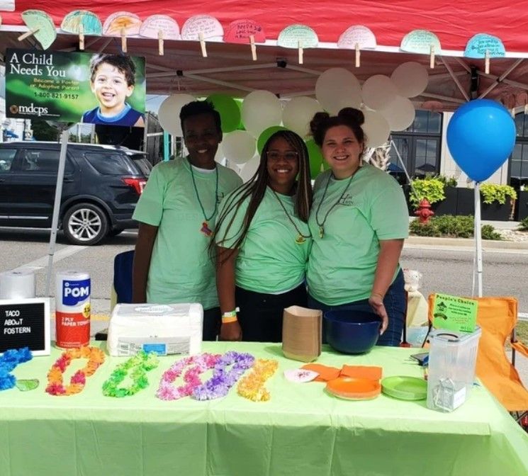 A group of people posing for a picture under a tent that says a child needs you