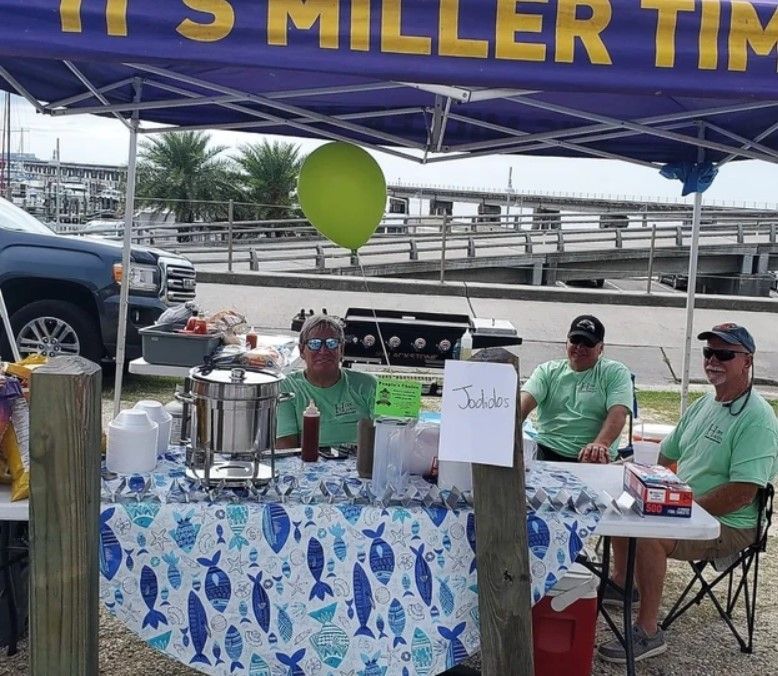 A man sitting at a table under a tent that says it 's miller tim
