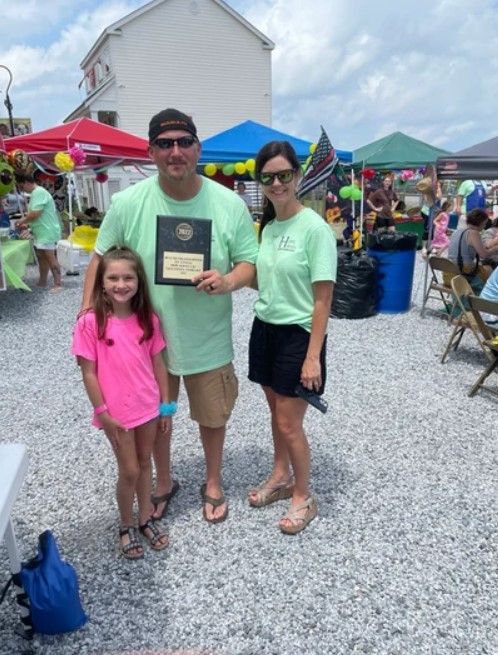 A man and woman standing next to a little girl holding a plaque