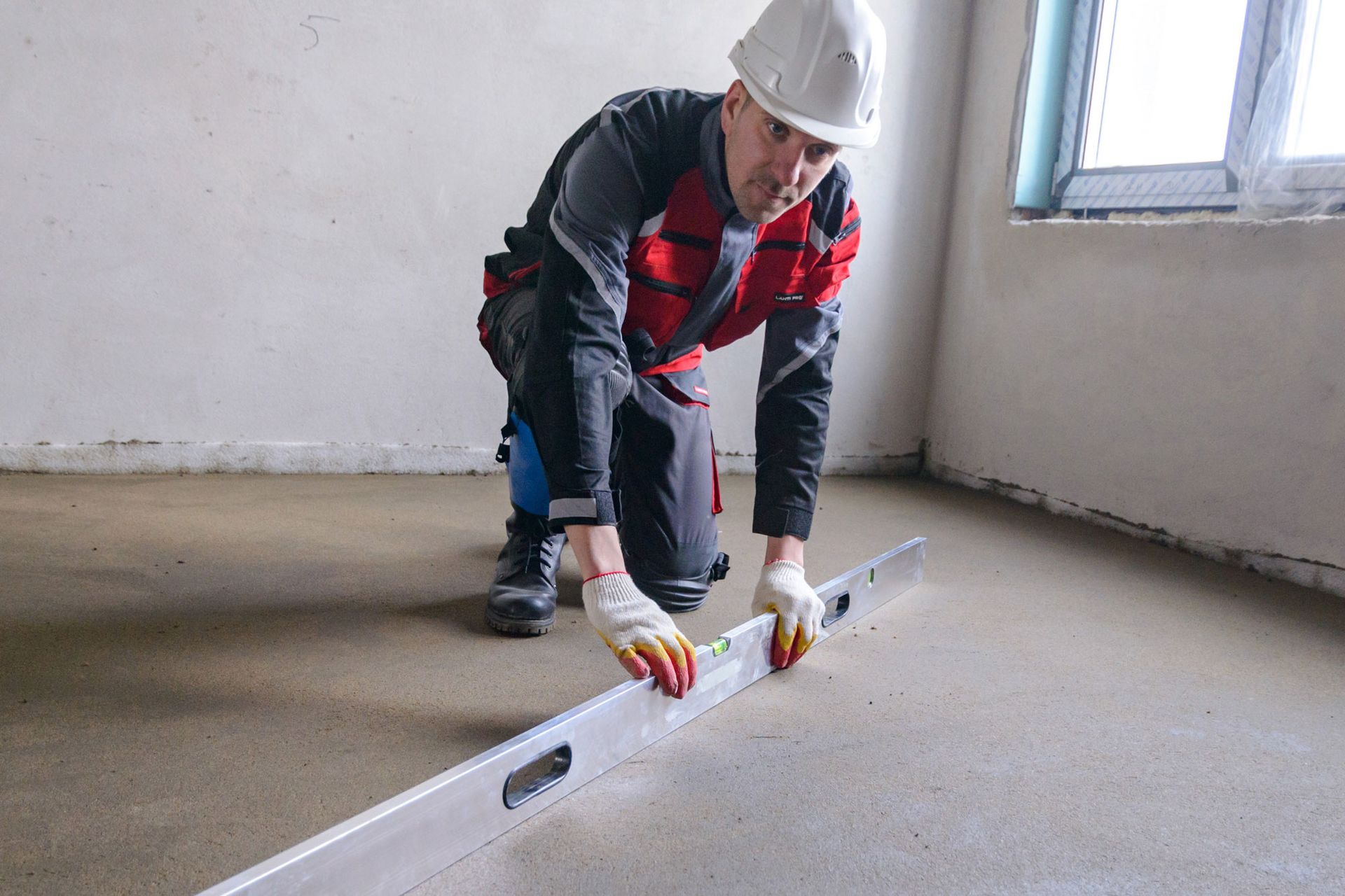 Wooden floor frame exposed, showing pipes and electrical wiring, likely a bathroom renovation in progress.