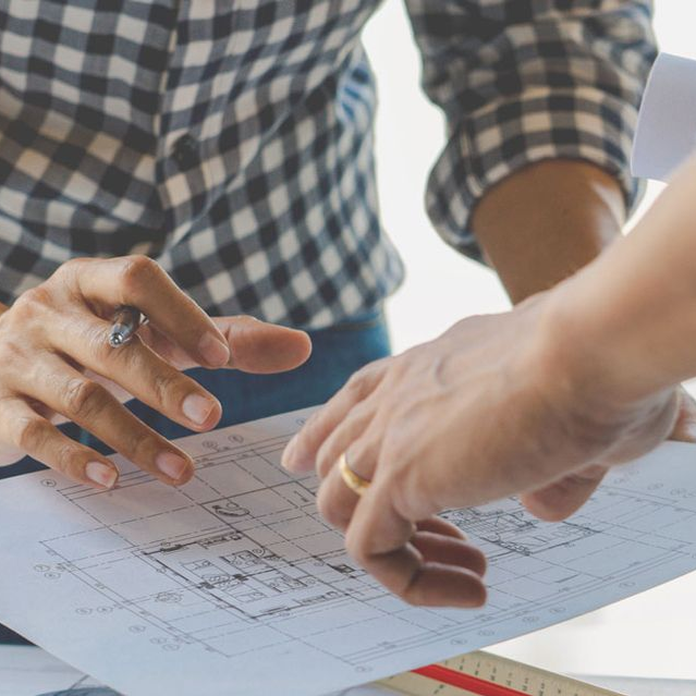Wooden floor frame exposed, showing pipes and electrical wiring, likely a bathroom renovation in progress.