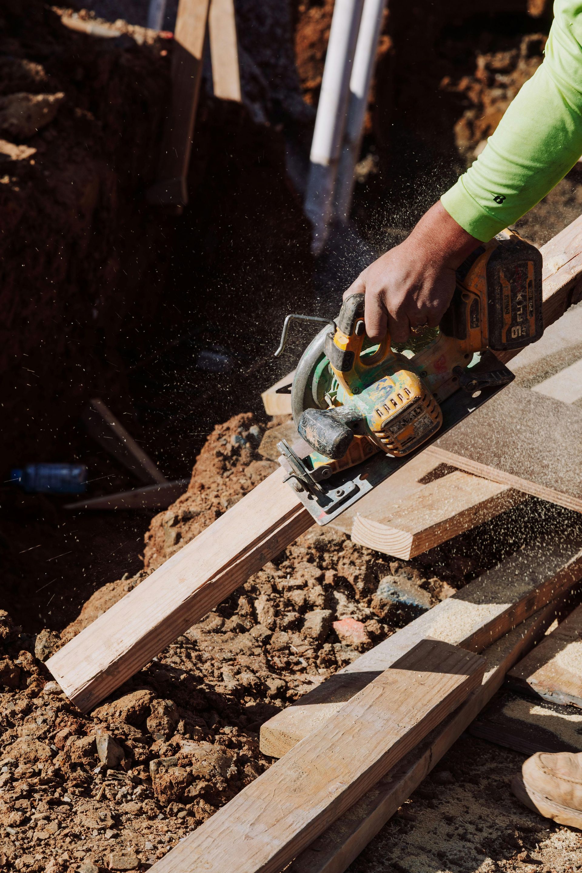 Foundation repair: brick supports a wooden beam, with plumbing and wiring visible underneath a house.