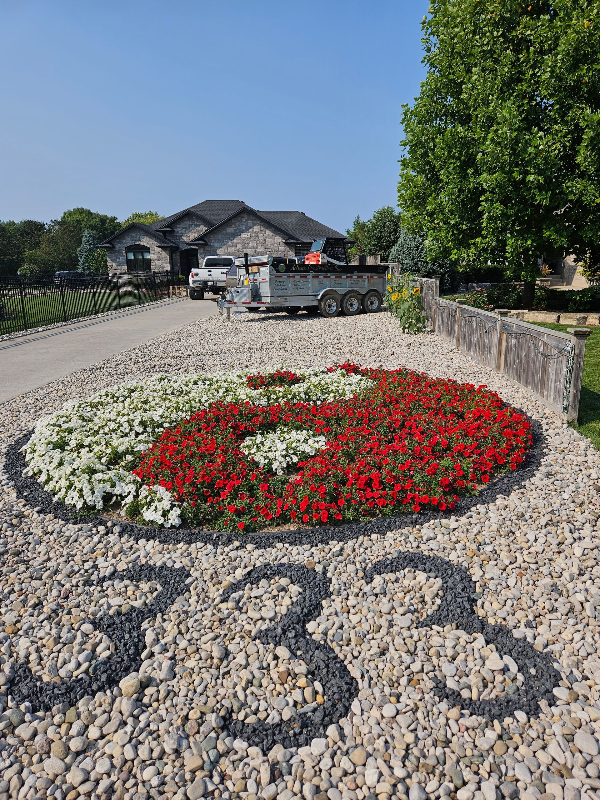 Front yard with a floral yin-yang, gravel driveway, house, and the address 