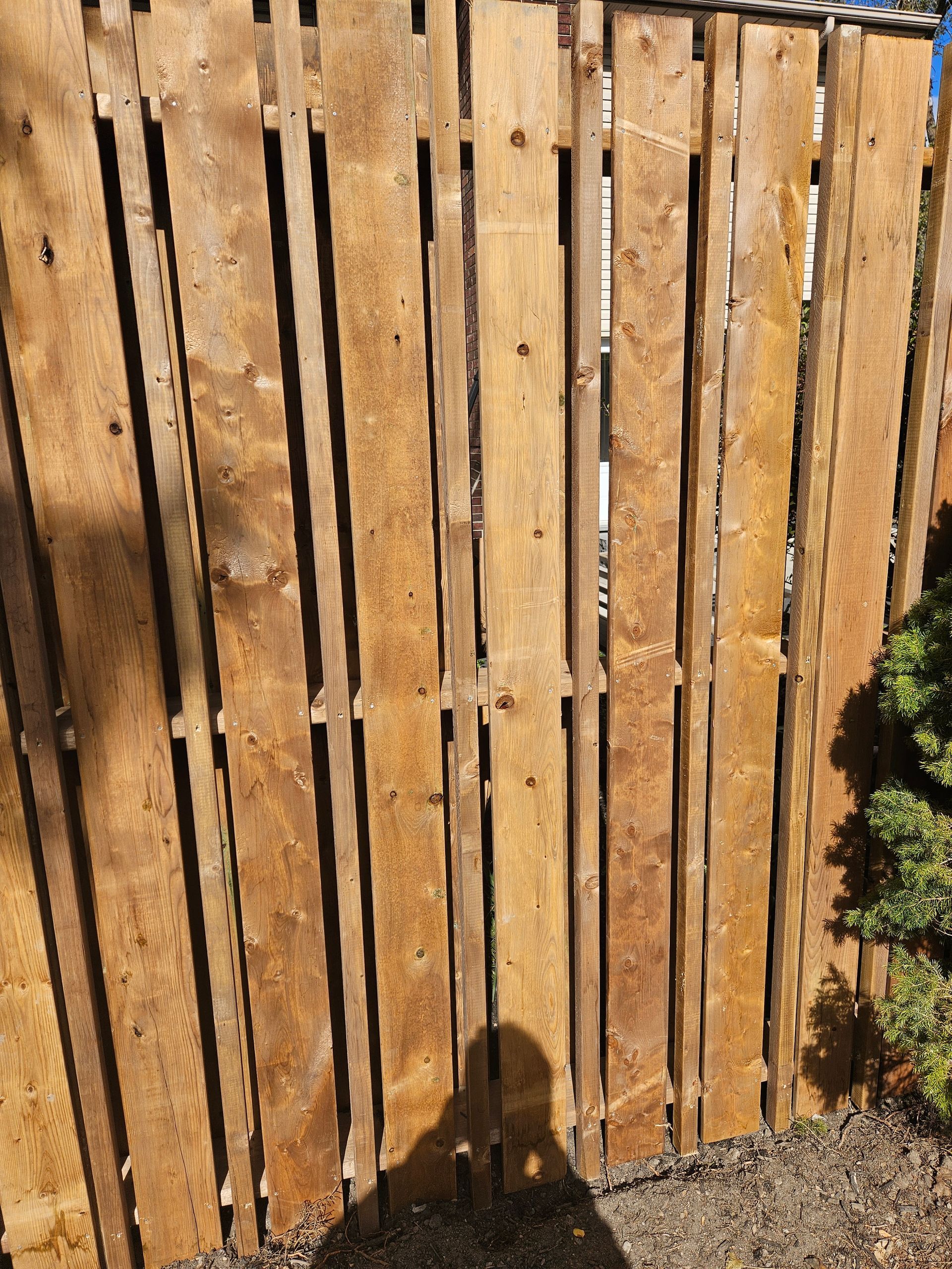 Wooden fence made from vertical planks, some dark shadows.
