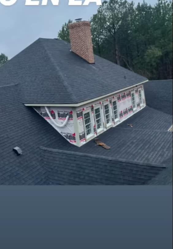 A house with a newly shingled roof and a row of windows in an angled alcove. A brick chimney stands tall.