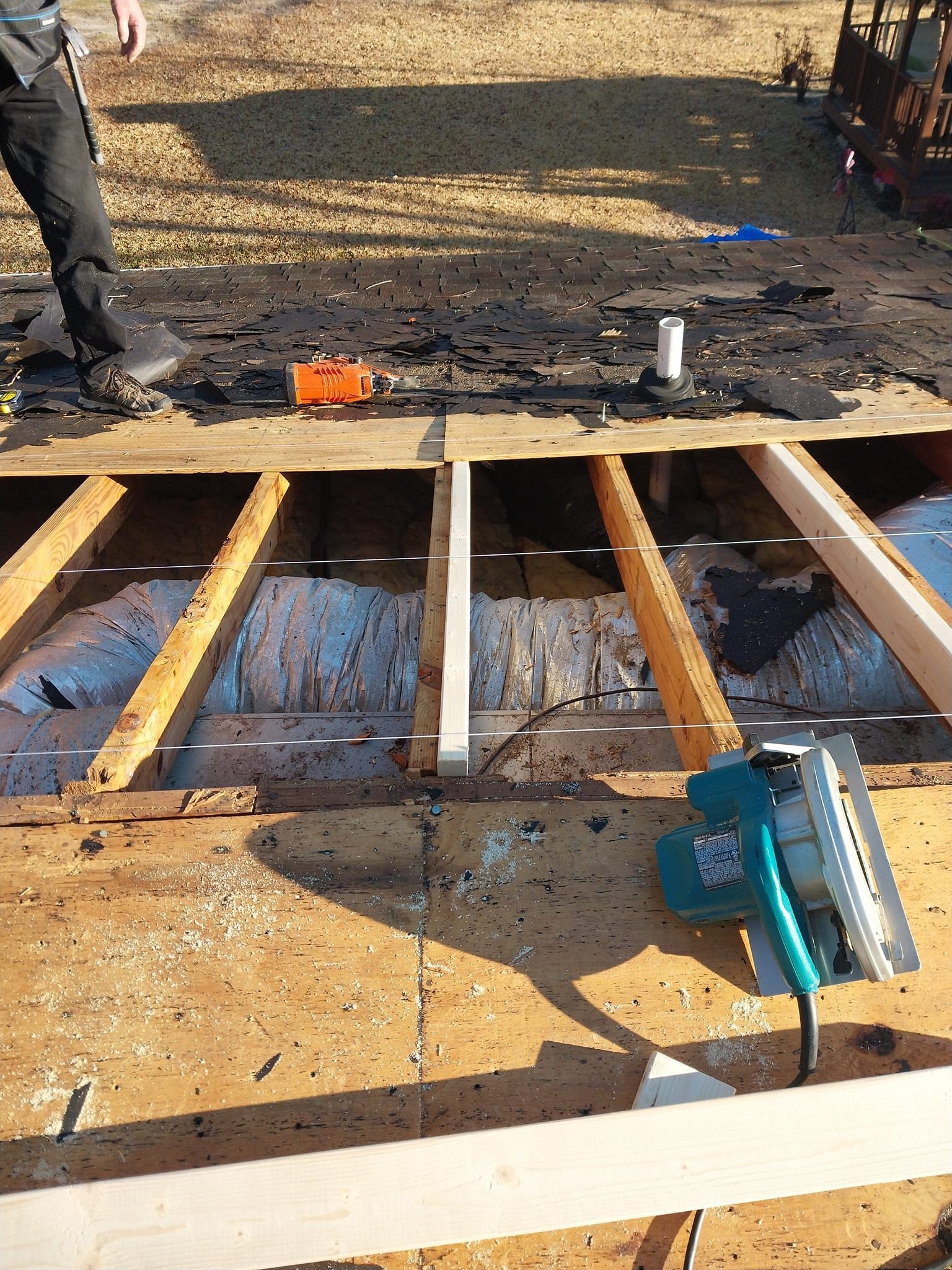 Construction on roof: person, exposed beams, circular saw, tools, debris.